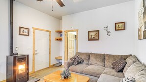 A living room with a sofa, a coffee table, a fireplace, and a ceiling fan. - Townsend Cottage on UTV & Snowmobile Trail! (Townsend)
