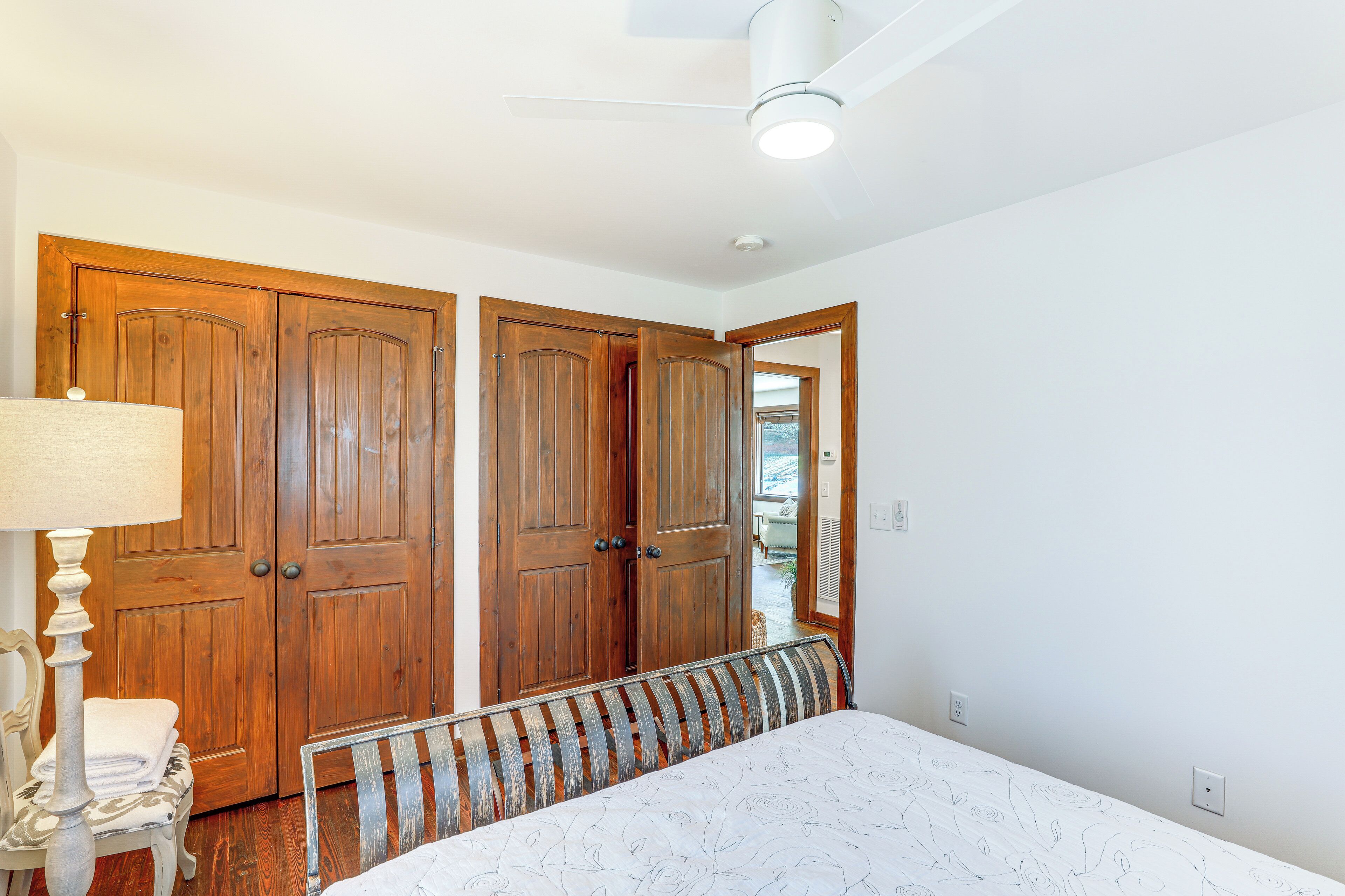 Une chambre à coucher avec un lit, une armoire en bois, une lampe et un ventilateur de plafond.