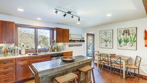 Een moderne keuken met houten kastjes, een groot eiland met krukken en kunstwerken aan de wand.