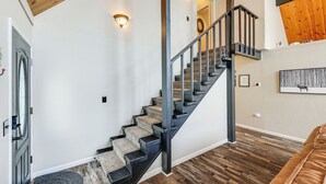 Una escalera con acabado de madera, barandilla negra y un rellano alfombrado.