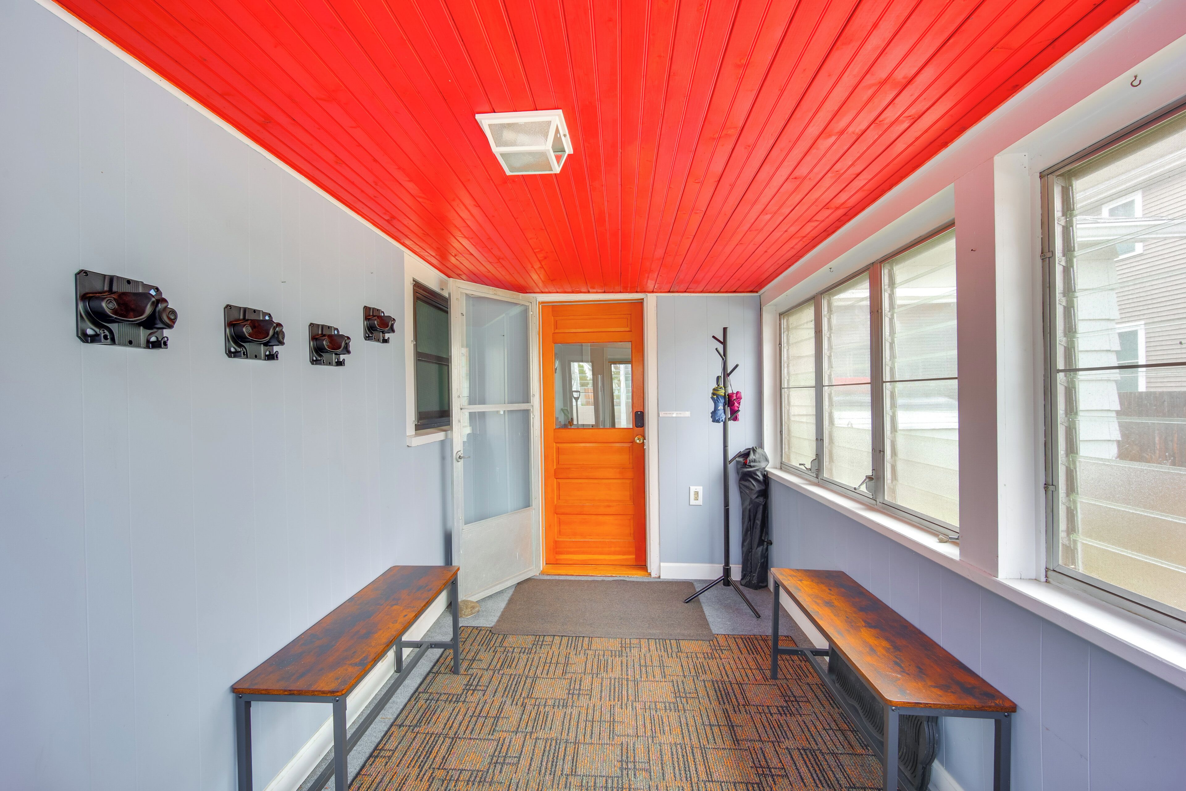 A hallway with a red ceiling, a wooden bench, a door, and a coat rack.