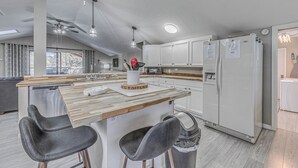 Une cuisine moderne dotée d’un îlot central, de tabourets de bar et d’un réfrigérateur.