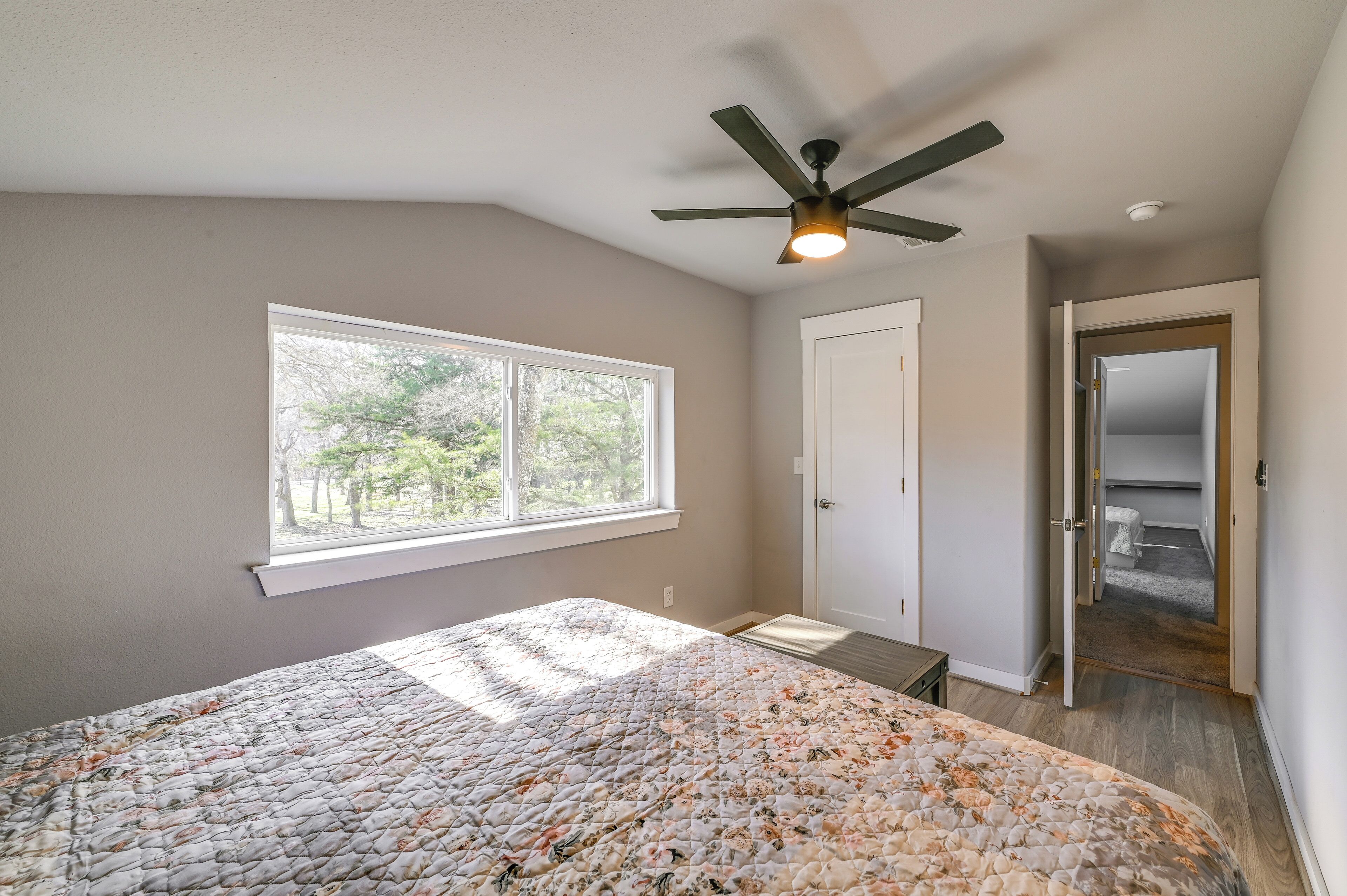 A bedroom with a bed, a ceiling fan, a window, and a door leading to a closet.