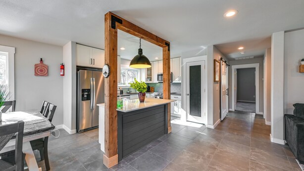 A modern kitchen with a central island, stainless steel appliances, and a wooden archway.