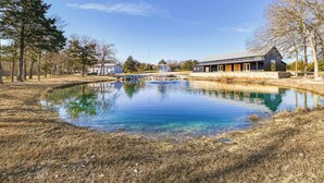 A serene lakeside setting with a modern building featuring large windows and a stone pathway leading to a dock.