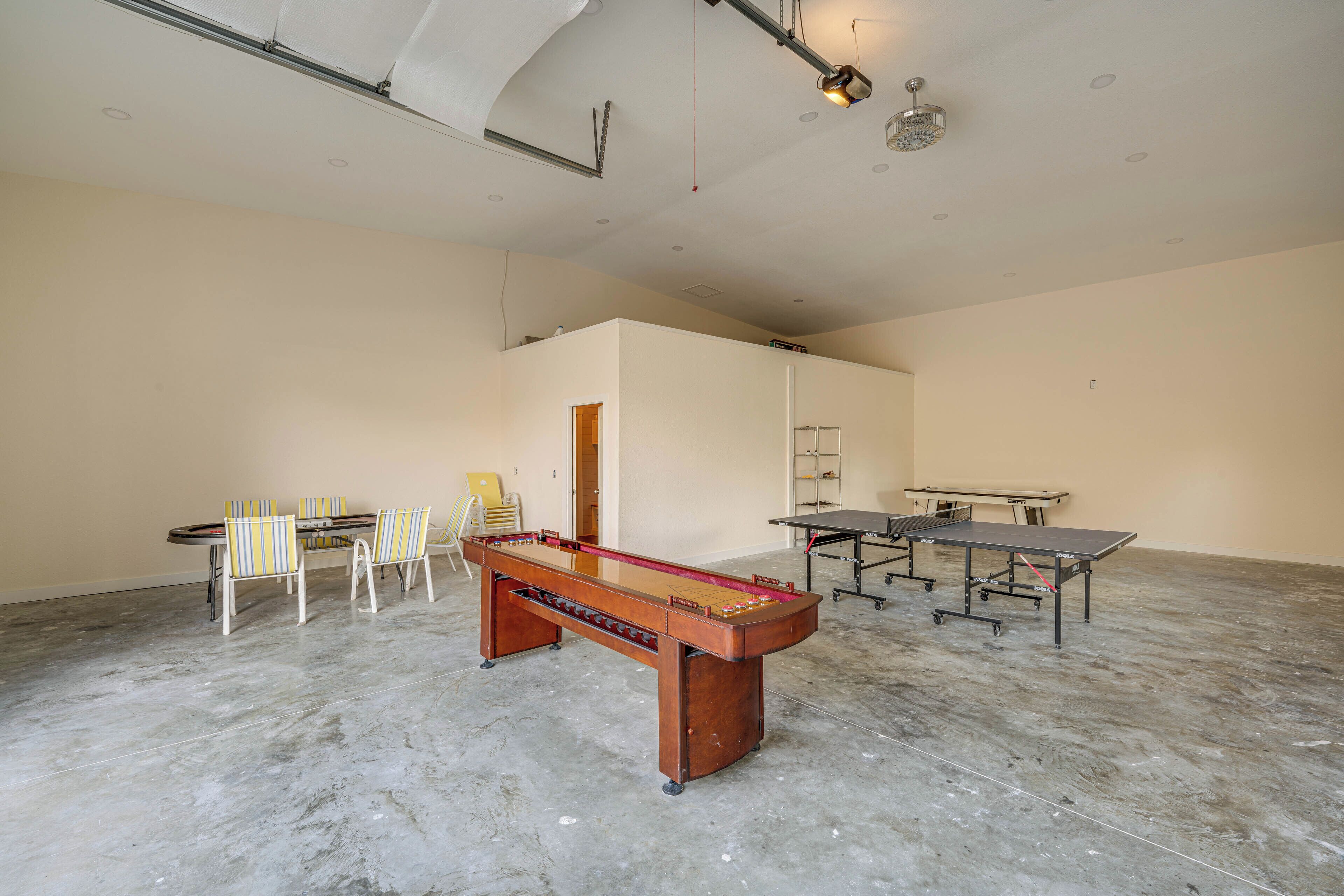 A spacious room with a foosball table, ping pong table, and chairs.