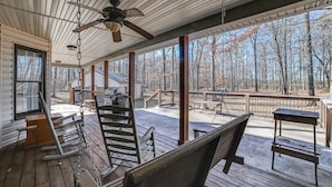 A covered porch with wooden rocking chairs, a ceiling fan, and a view of a forest. - Clarksville Home w/ Porch & Fishing Pond Access! (Clarksville)