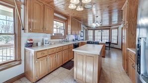A spacious kitchen with wooden cabinets, a large island, and a dishwasher. - Clarksville Home w/ Porch & Fishing Pond Access! (Clarksville)