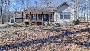 A two-story house with a front porch, a garage, and a small front yard with leaf-covered ground. - Clarksville Home w/ Porch & Fishing Pond Access! (Clarksville)