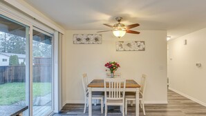 Un espace repas comprenant une table et des chaises, un ventilateur de plafond et des œuvres d’art accrochées aux murs.
