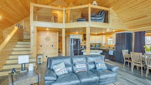 Une cabane spacieuse avec une chambre à coucher en mezzanine, un coin repas et une cuisine.
