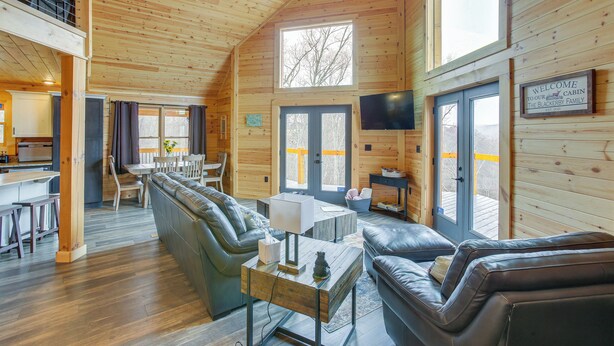 Un intérieur de cabine spacieux comprenant une chambre en mezzanine, un coin repas et un salon aménagé avec des canapés en cuir et une table basse.