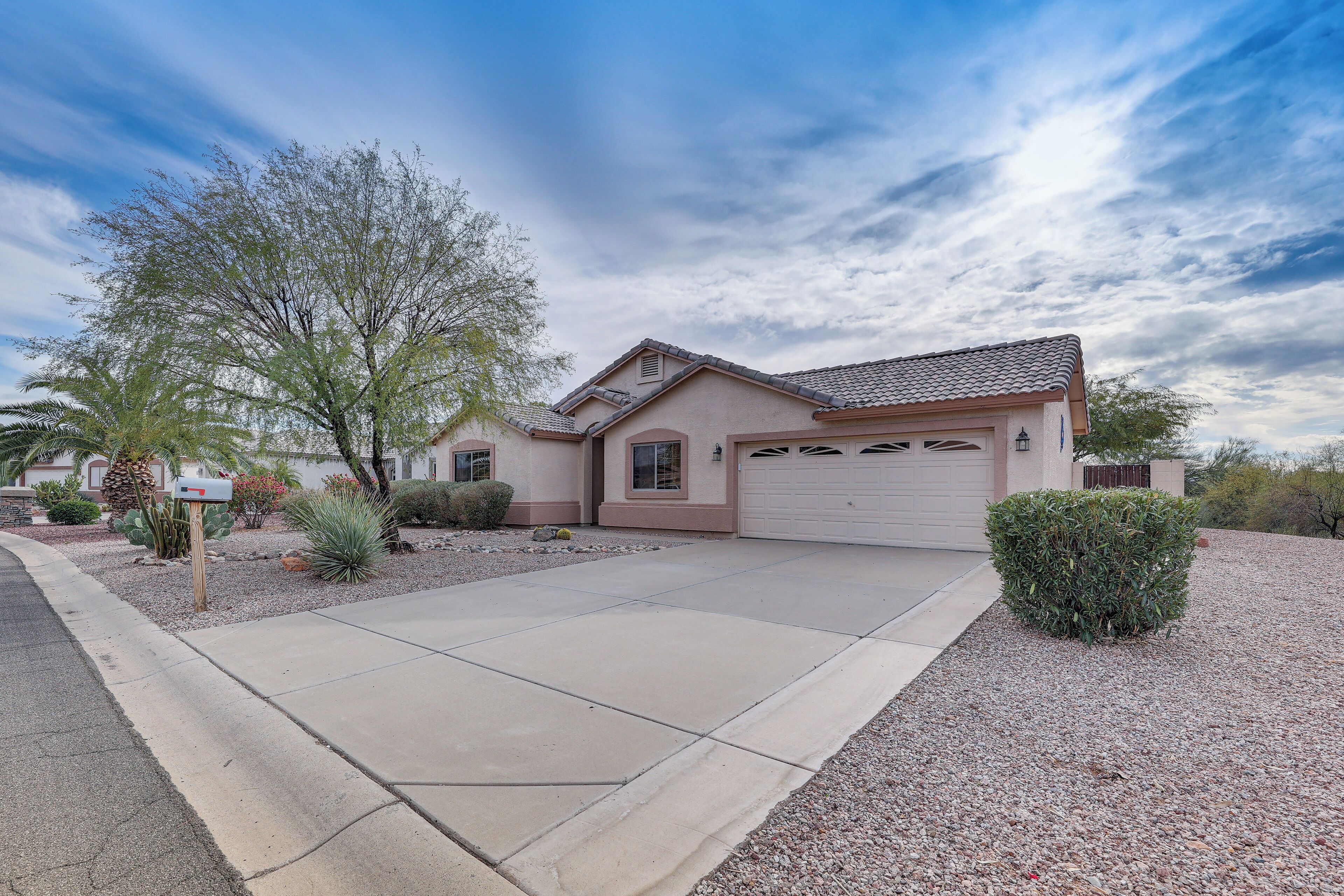 A residential house with a garage, a driveway, and a well-maintained front yard with various plants.