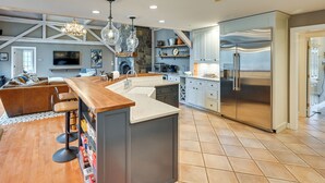 A modern kitchen with a central island, bar stools, a built-in oven, and a stainless steel refrigerator. - Monterey Home w/ Hot Tub, Pool & Game Room! (Monterey)