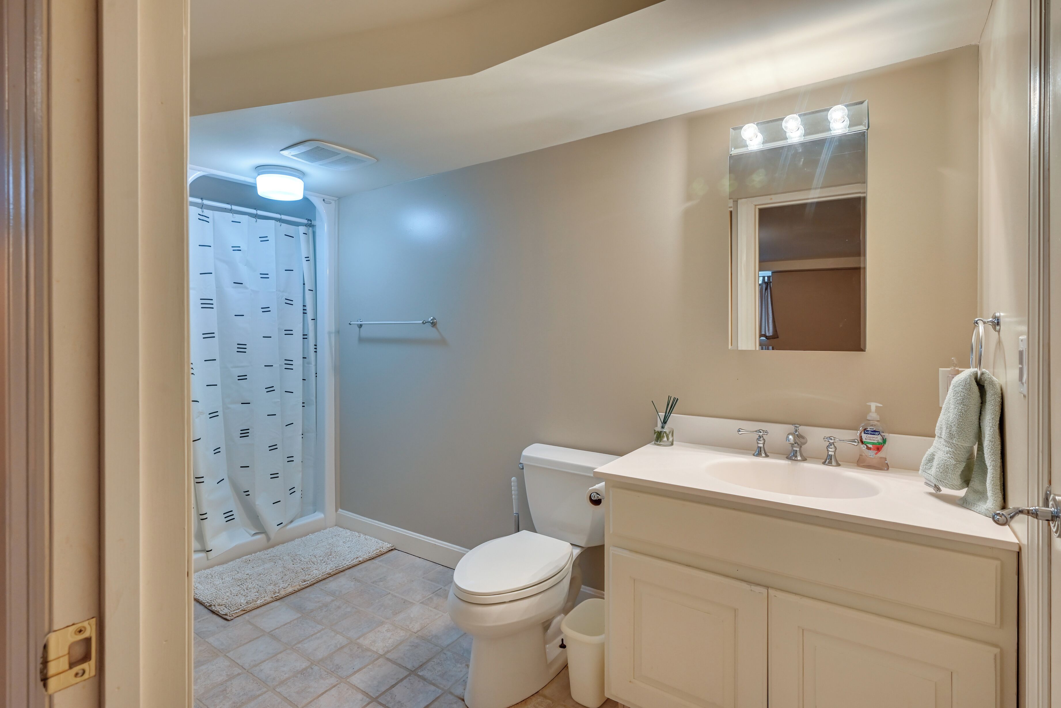 A bathroom with a toilet, sink, and mirror.