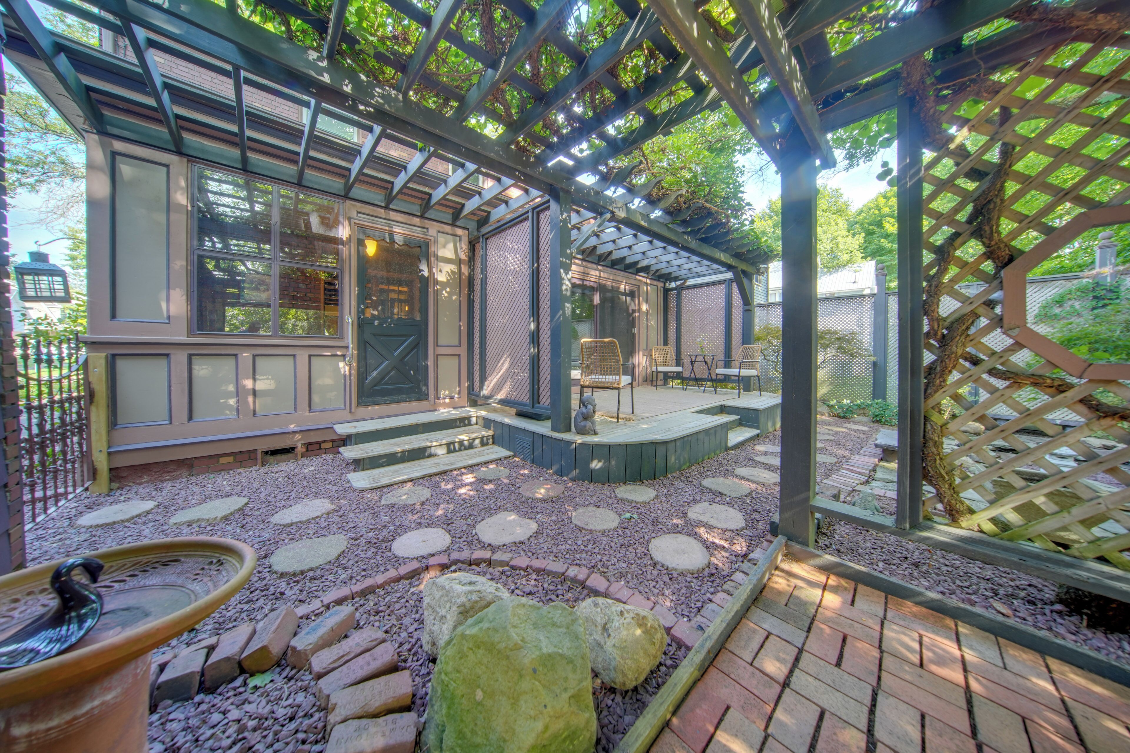 A covered patio area with a seating arrangement, a decorative stone pathway, and a pergola structure.