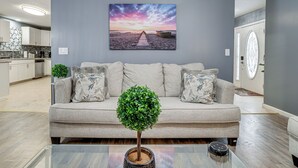 A modern living room with a grey sofa, a small potted plant, and a glass coffee table. - Pennsylvania Home w/ Hot Tub: 7 Mi to Kalahari! (Tobyhanna)