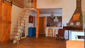 A spacious living area with a wooden staircase, a kitchen with a brick backsplash, and a cozy seating area. - Vista al Mar, Piscina y Paz: tu Escape Perfecto en Esta Casa Rural Única (Sant Miquel)