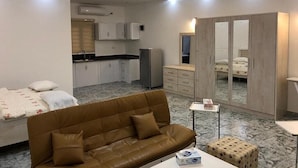 A compact living space with a sofa, a small table, a wardrobe, and a kitchenette. - Bamboo Beach Resort (Monrovia)