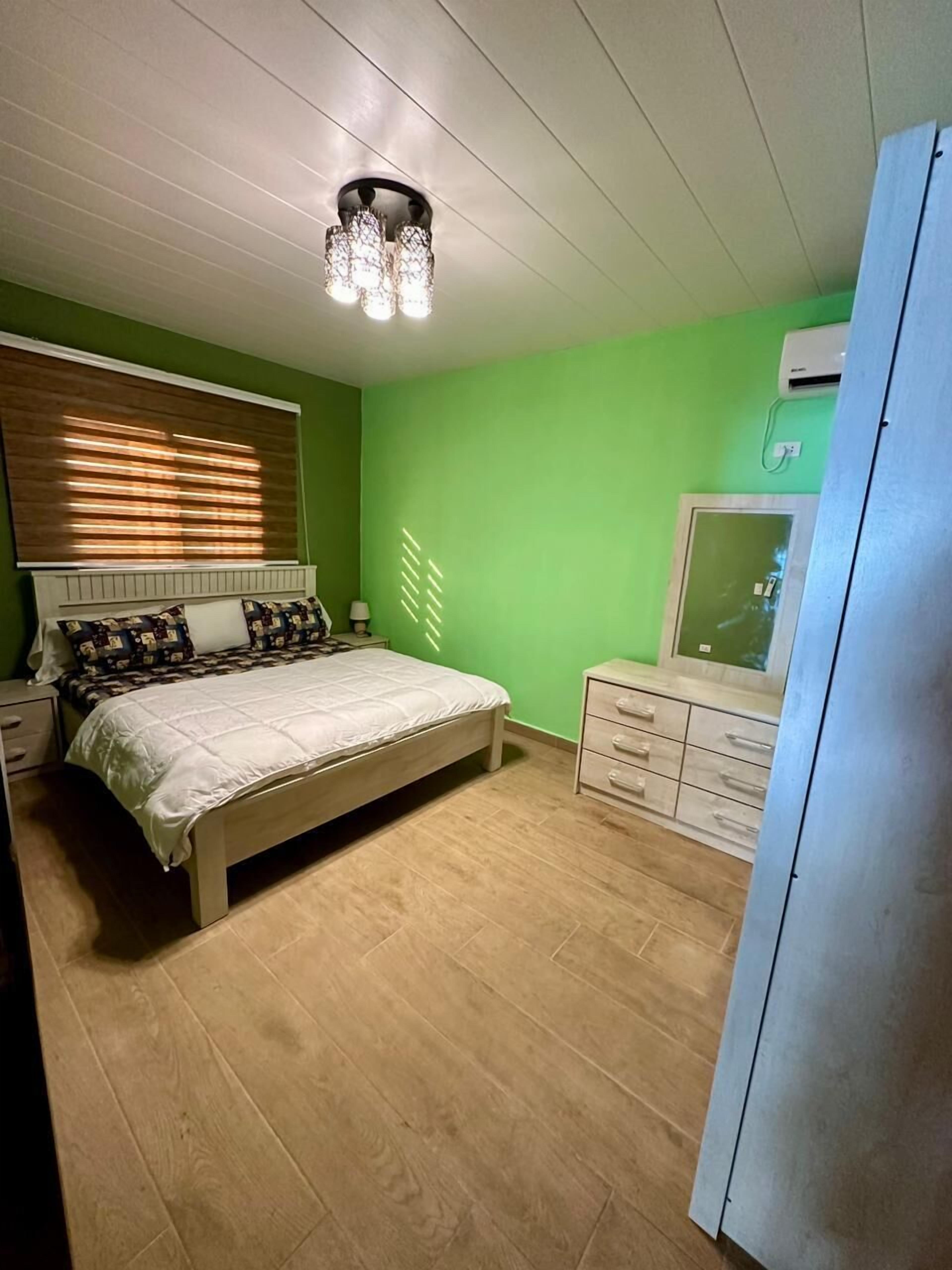 A bedroom with a bed, bedside tables, a dresser, and a ceiling light fixture.
