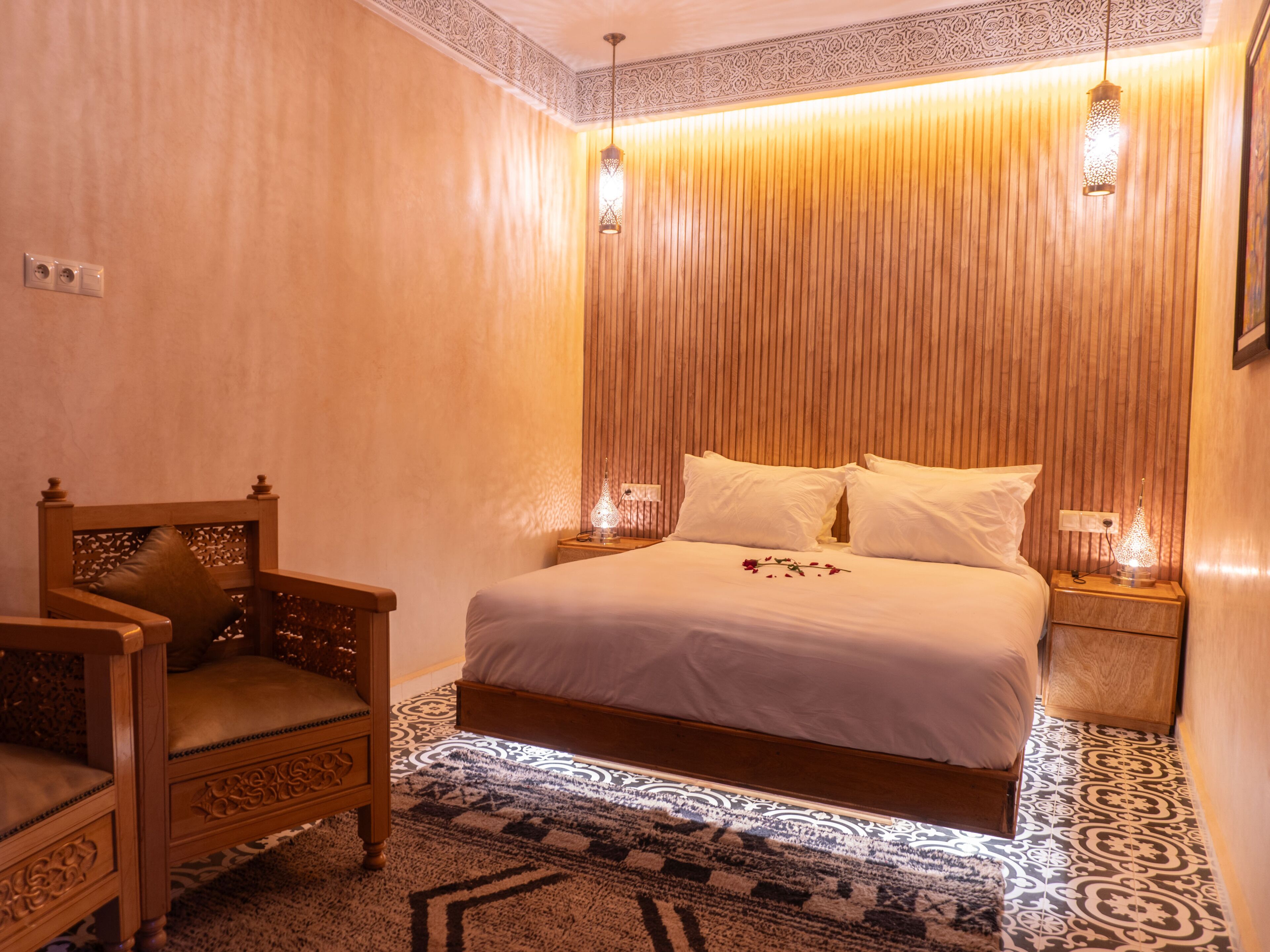 A bedroom with a wooden bed, a wooden chair, and two bedside lamps.