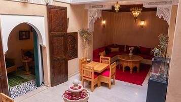A traditional Moroccan interior with a seating area, a fountain, and ornate decor.
