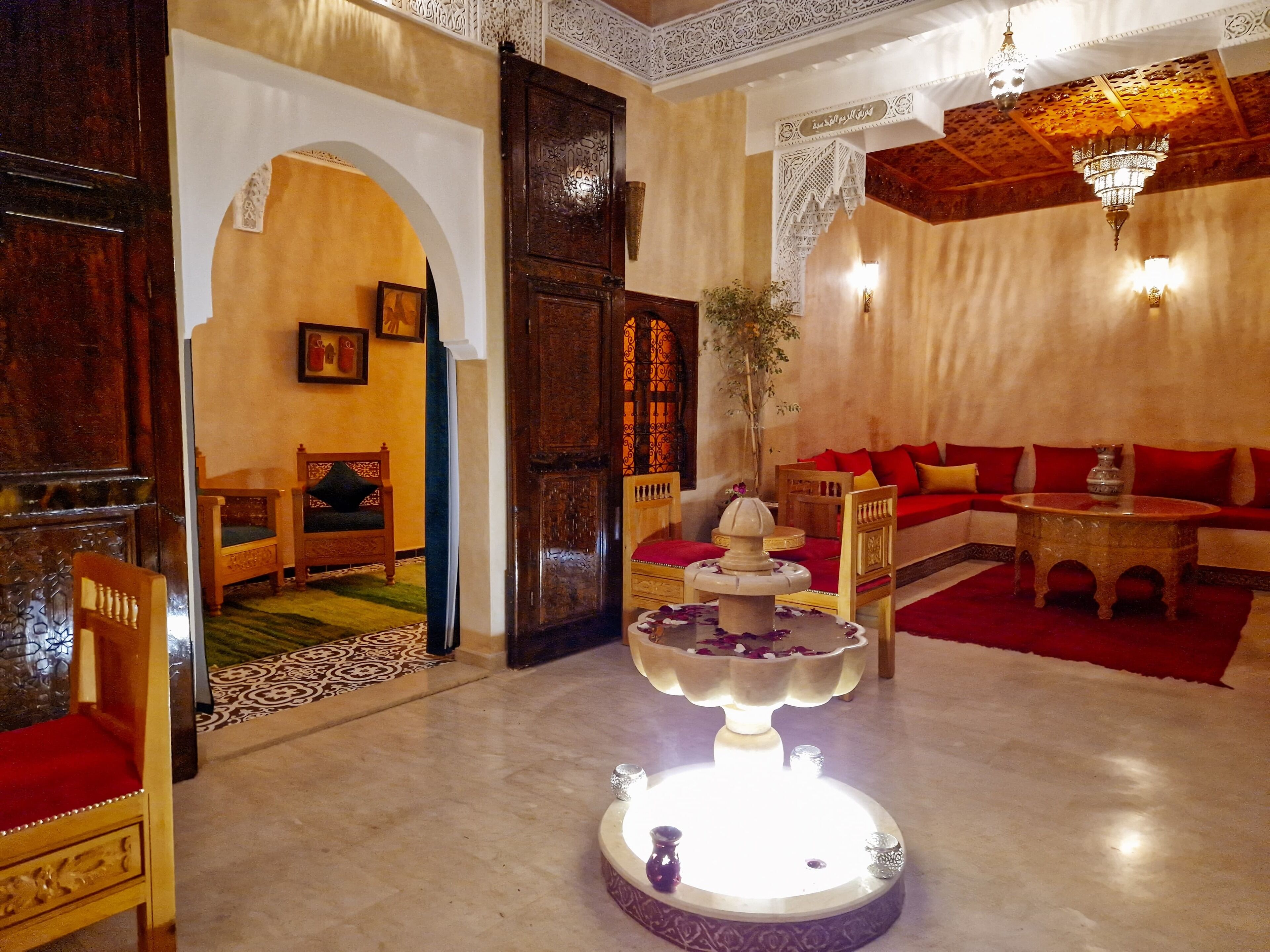 Un interior tradicional con una fuente central, muebles de madera y decoración ornamentada.