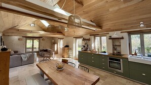 Une cuisine spacieuse avec des poutres en bois, un coin repas et un salon confortable avec un canapé et une table.