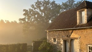 Une maison en pierre avec un toit de tuiles, une petite fenêtre et une porte.
