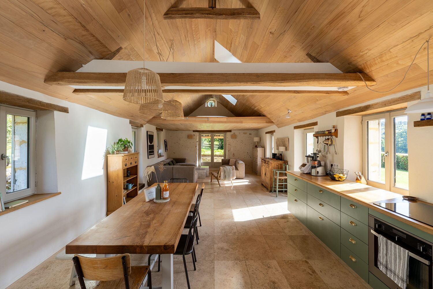 Une cuisine spacieuse avec des poutres en bois, un coin repas et une vue sur l’extérieur.