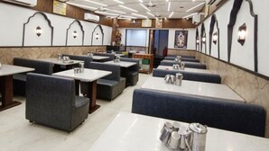 A restaurant with booths and tables, some with tea sets. - Hotel Kant by GoHotels - Near Shree Dwarkadhish Temple (Dwarka)
