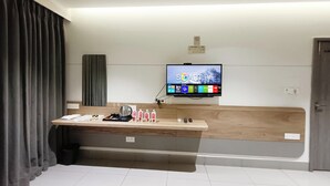A modern hotel room with a flat-screen TV mounted on the wall, a wooden bench, and a small table with toiletries. - Hotel Kant by GoHotels - Near Shree Dwarkadhish Temple (Dwarka)