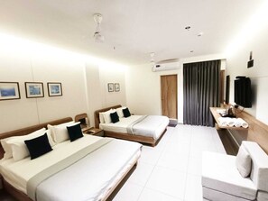 Habitación de hotel con dos camas, un escritorio, una silla, un televisor y la puerta del baño.