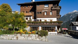 Un hotel de varios pisos con balcones, fachada de piedra y vistas a la montaña.