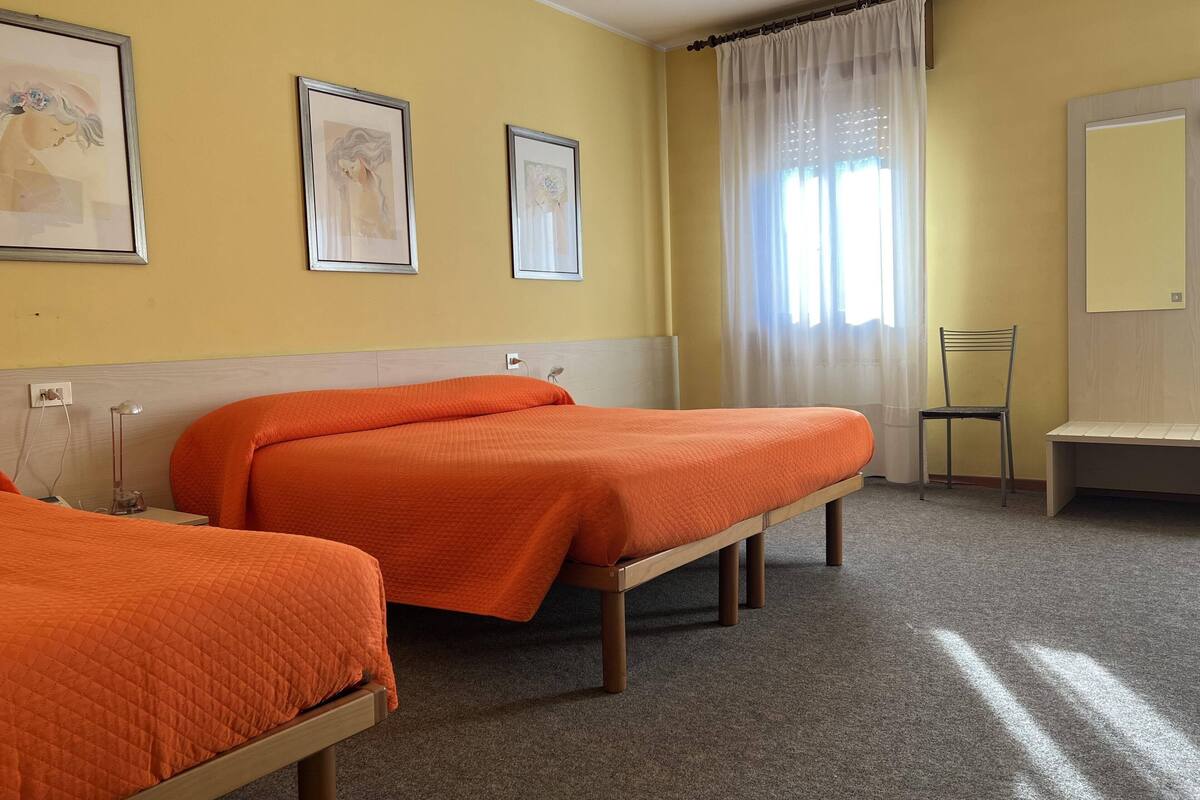 Habitación de hotel con dos camas, una silla y obras de arte en las paredes.