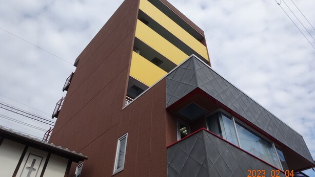 Un bâtiment moderne doté d’une conception architecturale originale, caractérisé par une combinaison de couleurs marron et jaune, et d’une section d’angle remarquable ornée d’un motif géométrique.