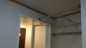 Une salle de bain avec une tringle à rideau de douche et des crochets, un porte-serviettes et un interrupteur.