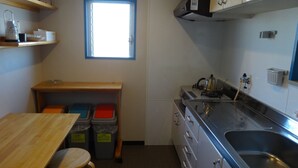 A compact kitchen with a window, wooden table, stools, and stainless steel appliances. - It has a kitchen, closet, shoe closet, washing machine, balcony and parking space. Clothes can be dried on the balcony, or room-dried. The 46 sq. m. of space is ideal for long-term stays. (大阪市)
