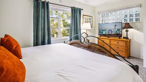 Une chambre d’hôtel avec un grand lit, une commode en bois, une télévision et une fenêtre avec des rideaux.