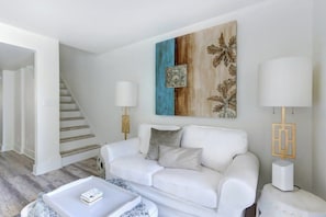 Un salon moderne avec un canapé blanc, une table basse et un tableau accroché au mur.