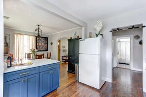 A kitchen with blue cabinets, a white refrigerator, and a wooden floor. - Shades of Blue on Park - Walk to Forsyth! (Savannah)