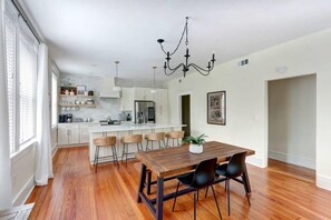 A modern kitchen with white cabinets, a wooden dining table, and black chairs.