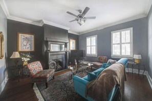 Ein Wohnzimmer mit Kamin, Deckenventilator und großem Fenster.