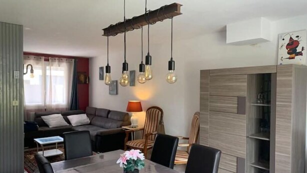 Una sala moderna con un sofá, una mesa de comedor con sillas y una lámpara.