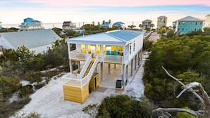 Une maison située sur la côte, dotée d’un balcon, d’une terrasse couverte et offrant une vue sur l’océan.