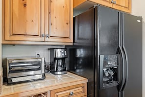 A kitchenette with a black refrigerator, a toaster, and a coffee maker.