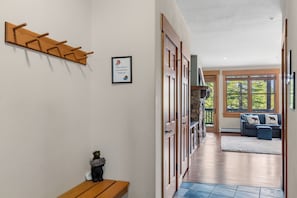 A hallway with a coat rack, a welcome sign, and a framed notice.