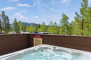 A hot tub area with a sign listing spa rules, surrounded by trees and a mountain in the background. - Charming Mountain Retreat in Keystone, Colorado (Keystone)