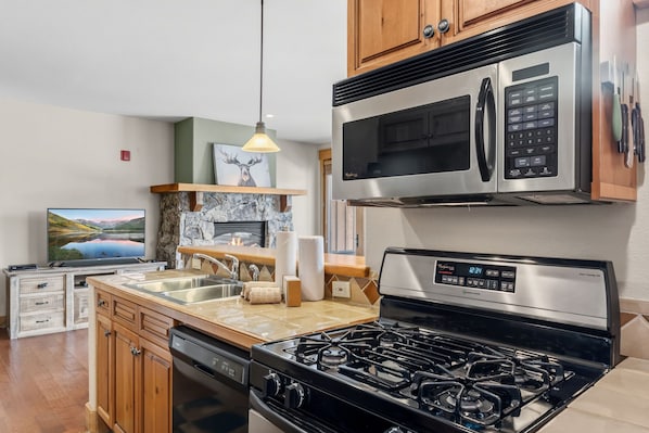 A modern kitchen with a gas stove, stainless steel appliances, and a stone fireplace.