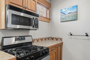 A kitchen with a stainless steel microwave, a gas stove, wooden cabinets, and a wall-mounted picture. - Charming Mountain Retreat in Keystone, Colorado (Keystone)